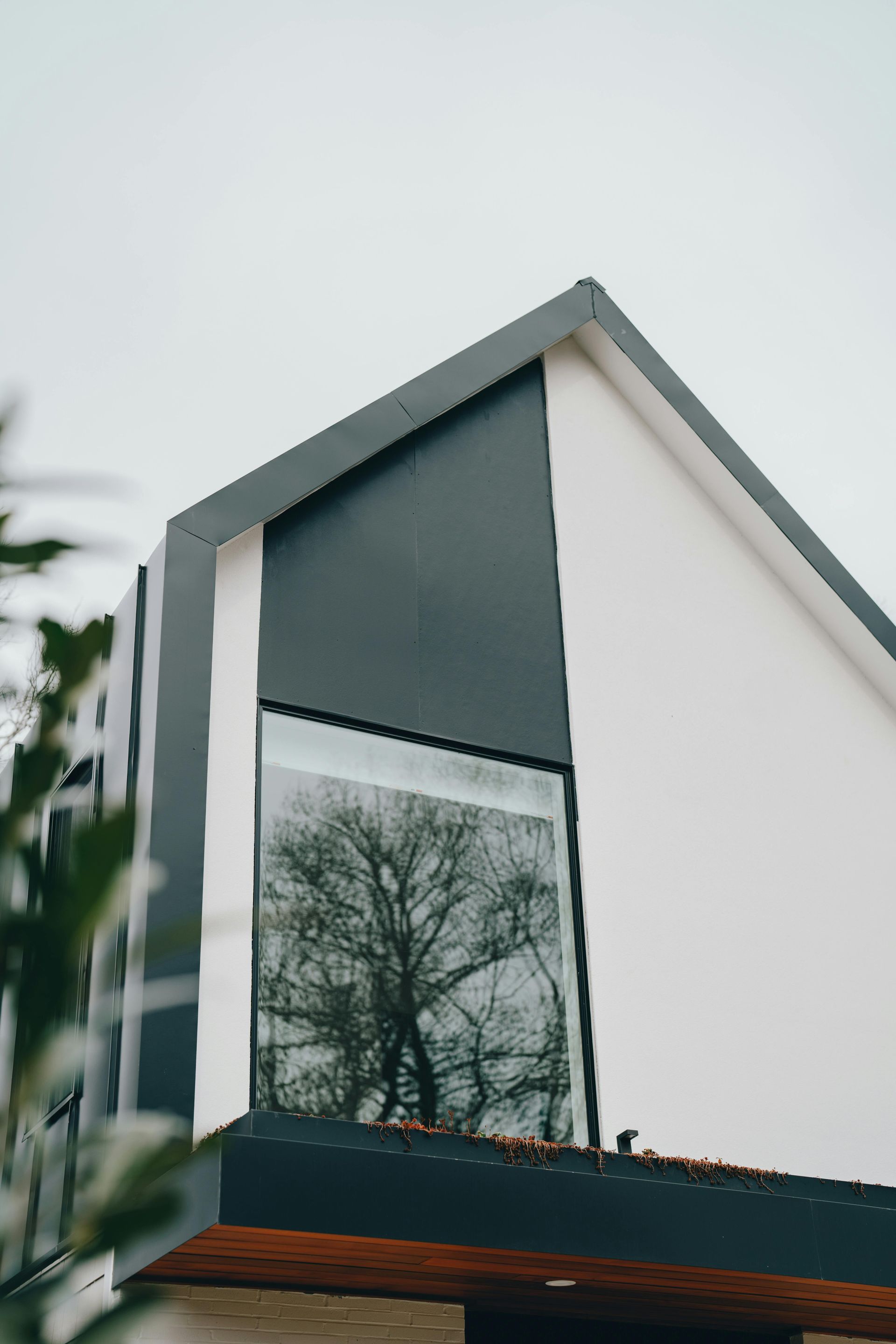 Modern house exterior with large reflective window and white-and-gray facade