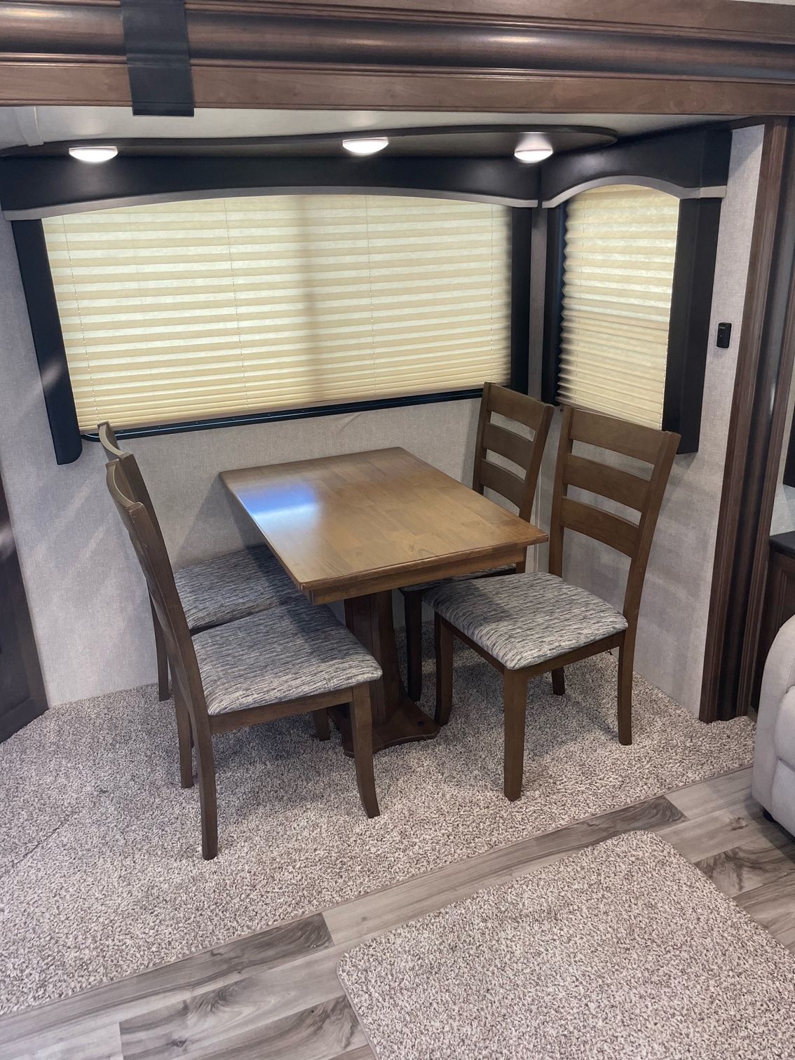 A dining room in a rv with a table and chairs.