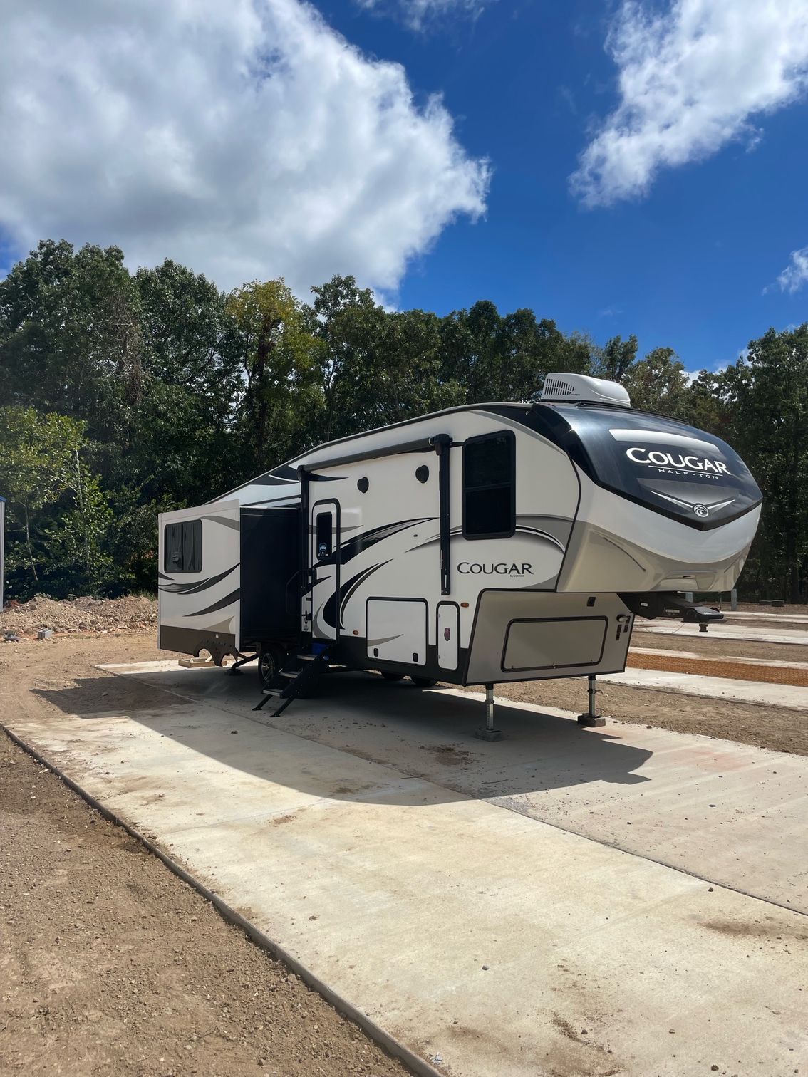 A white and black rv is parked on the side of a road.