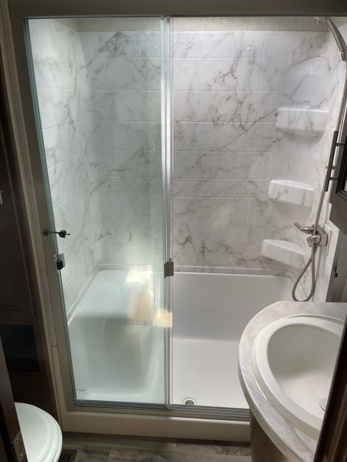 A bathroom with a shower , sink and toilet.