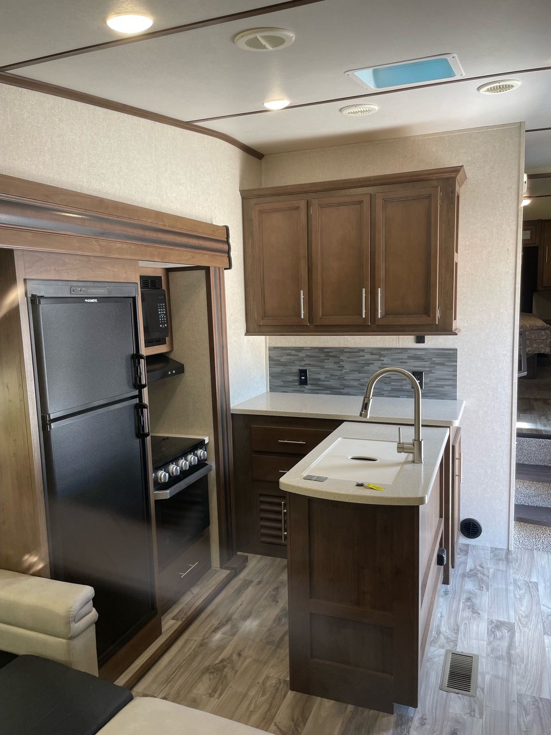 A kitchen in a rv with a sink , refrigerator and stove.