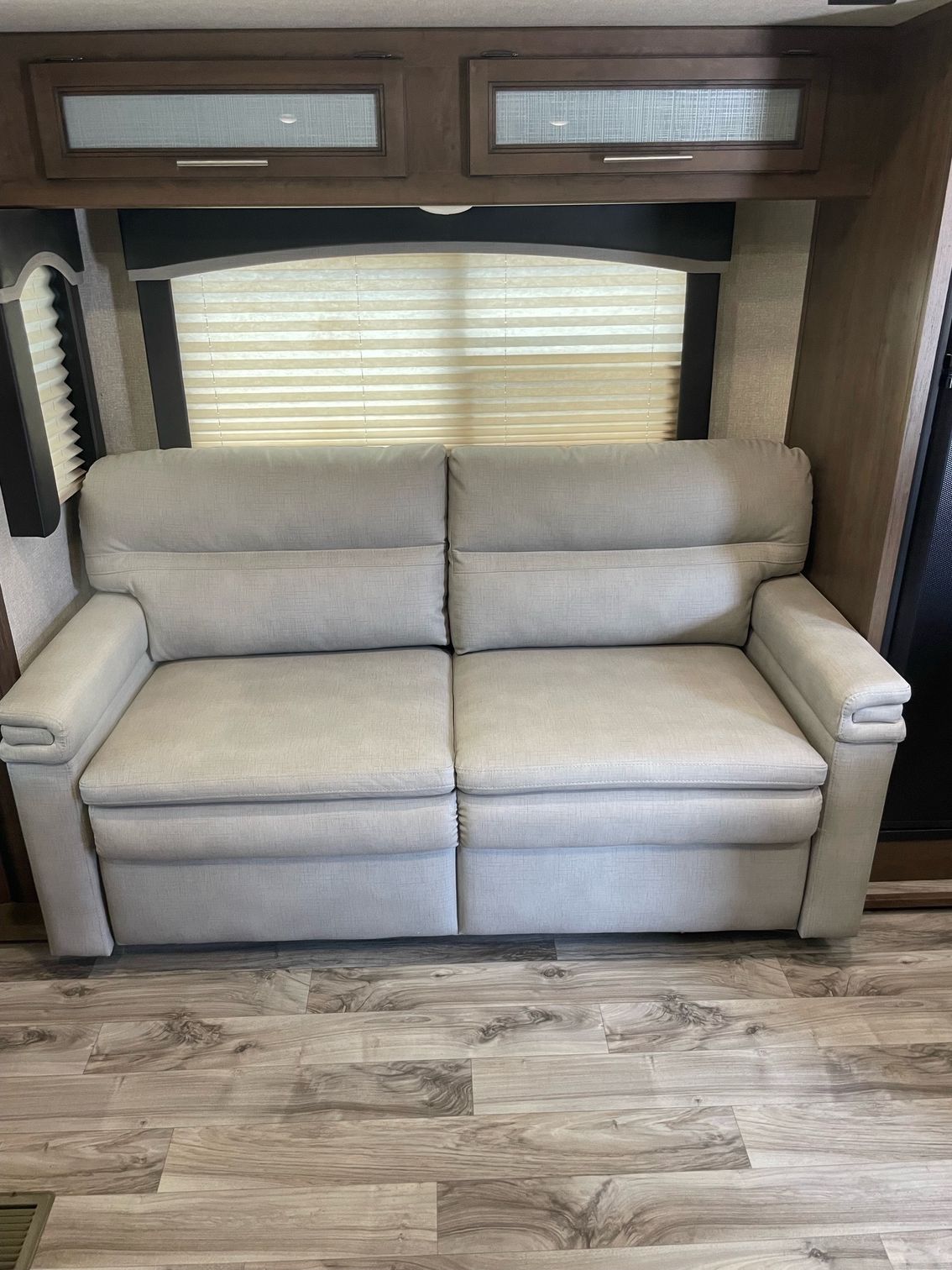 A white couch is sitting in a rv next to a window.