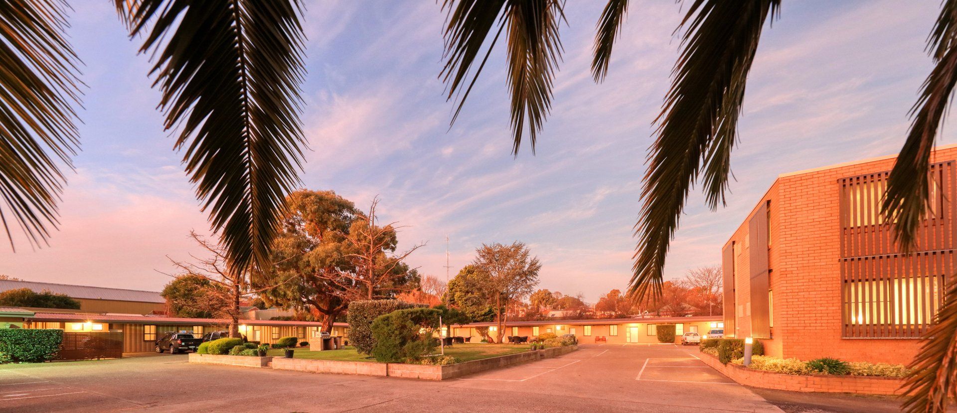 Sunset view of a campus courtyard with palm trees and modern brick buildings