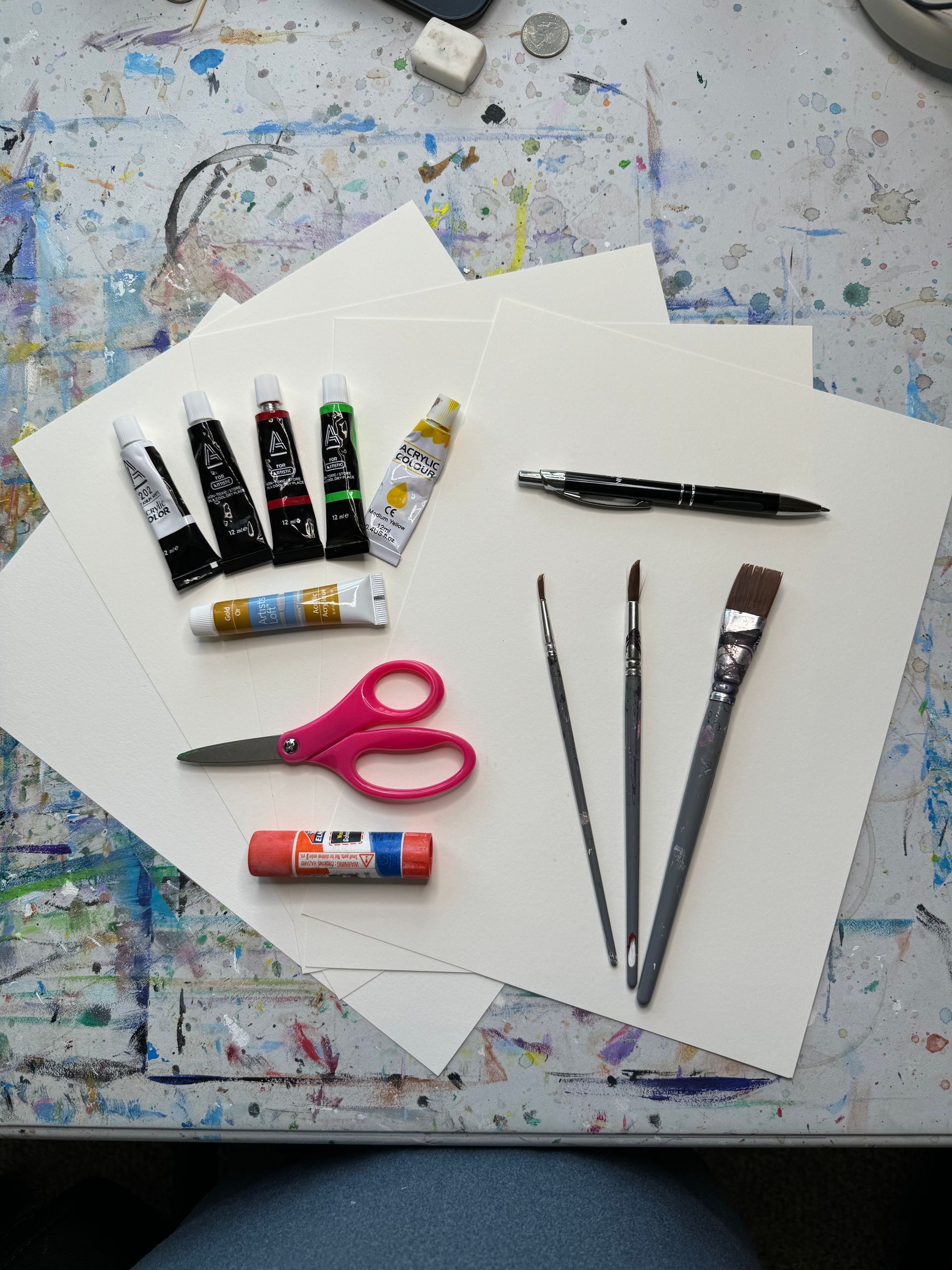 A bunch of art supplies on a table including a pair of scissors