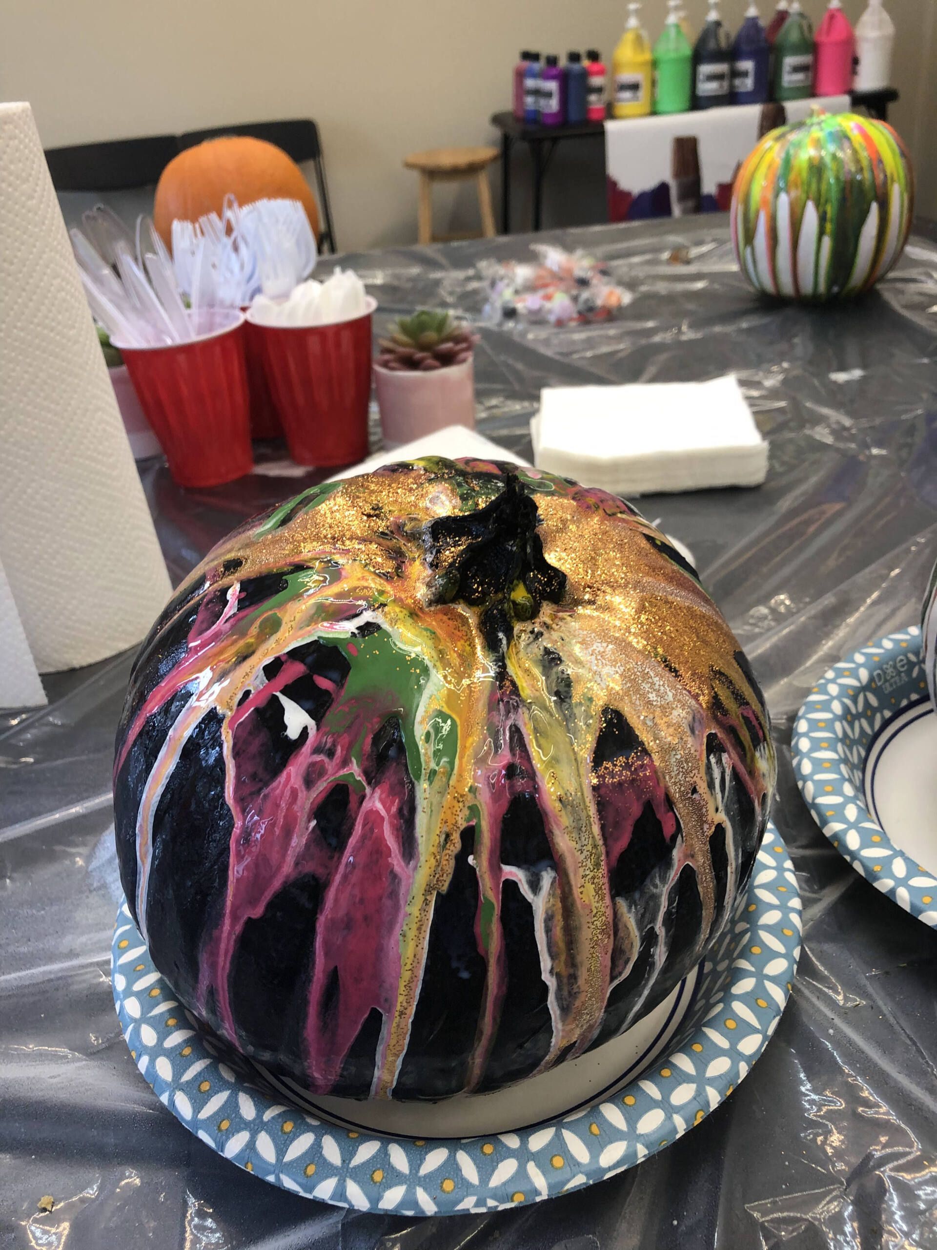 A colorful pumpkin is sitting on a paper plate on a table.