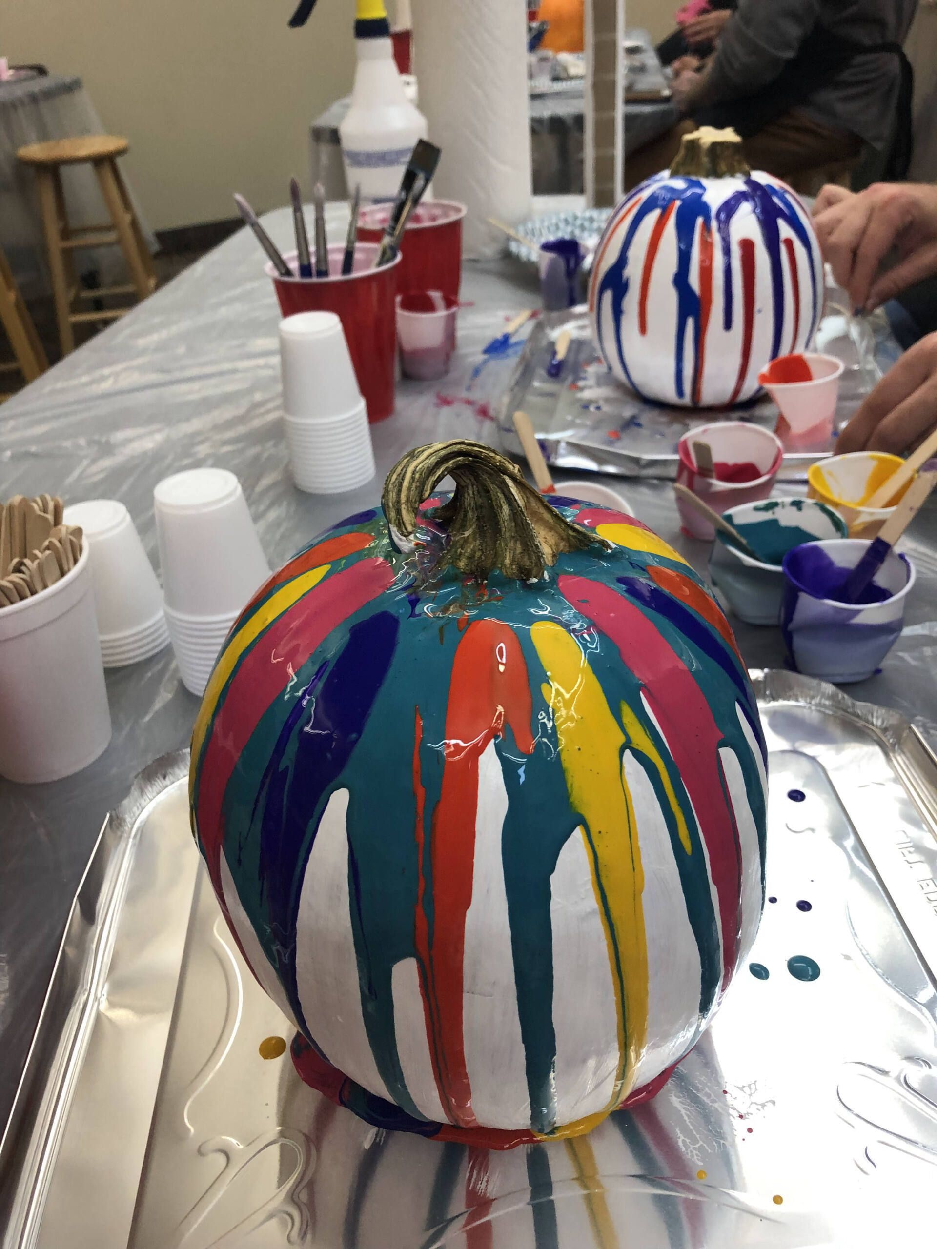 A colorful pumpkin is sitting on a tray on a table.