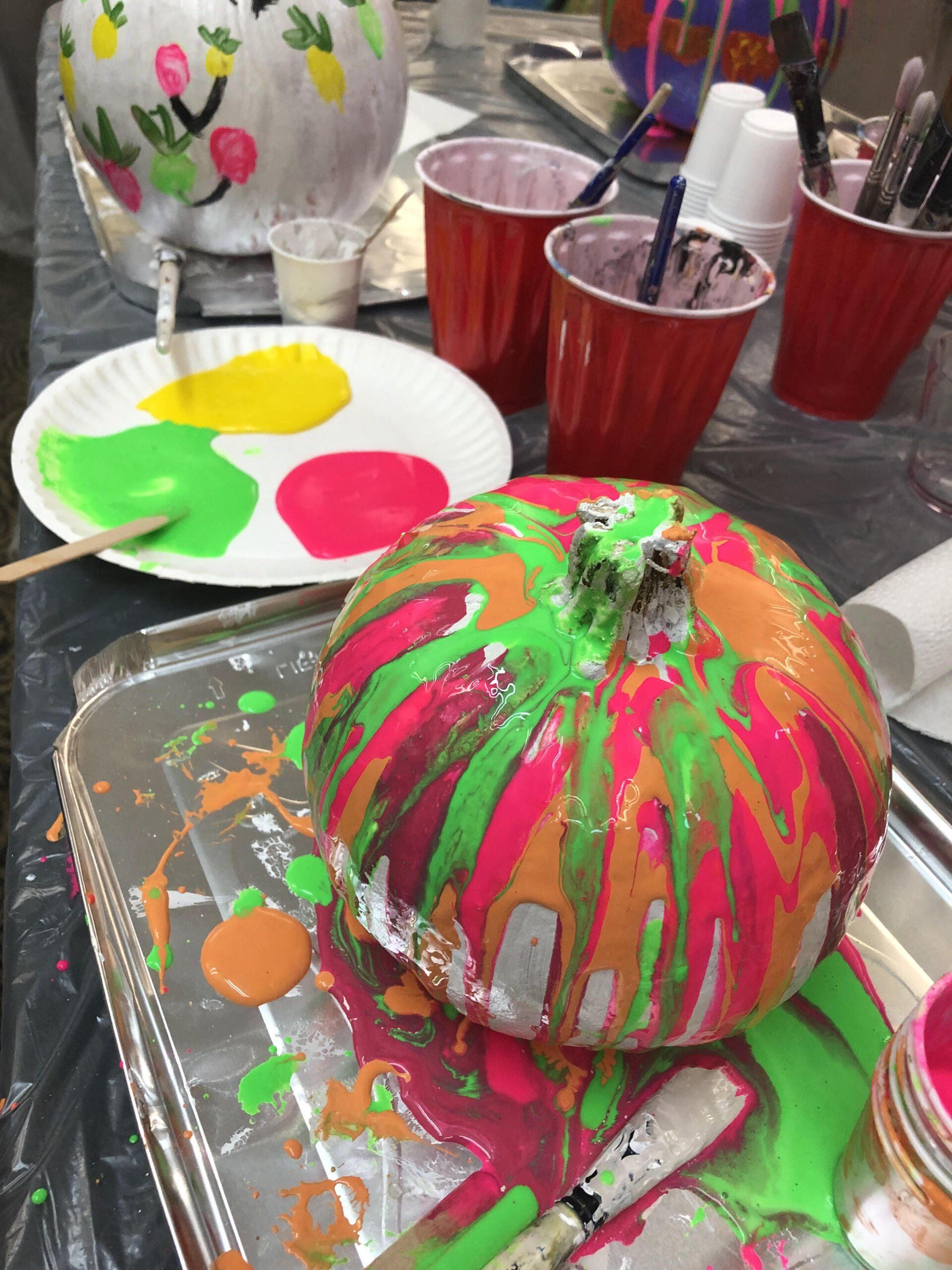 A pumpkin is sitting on a tray covered in paint.