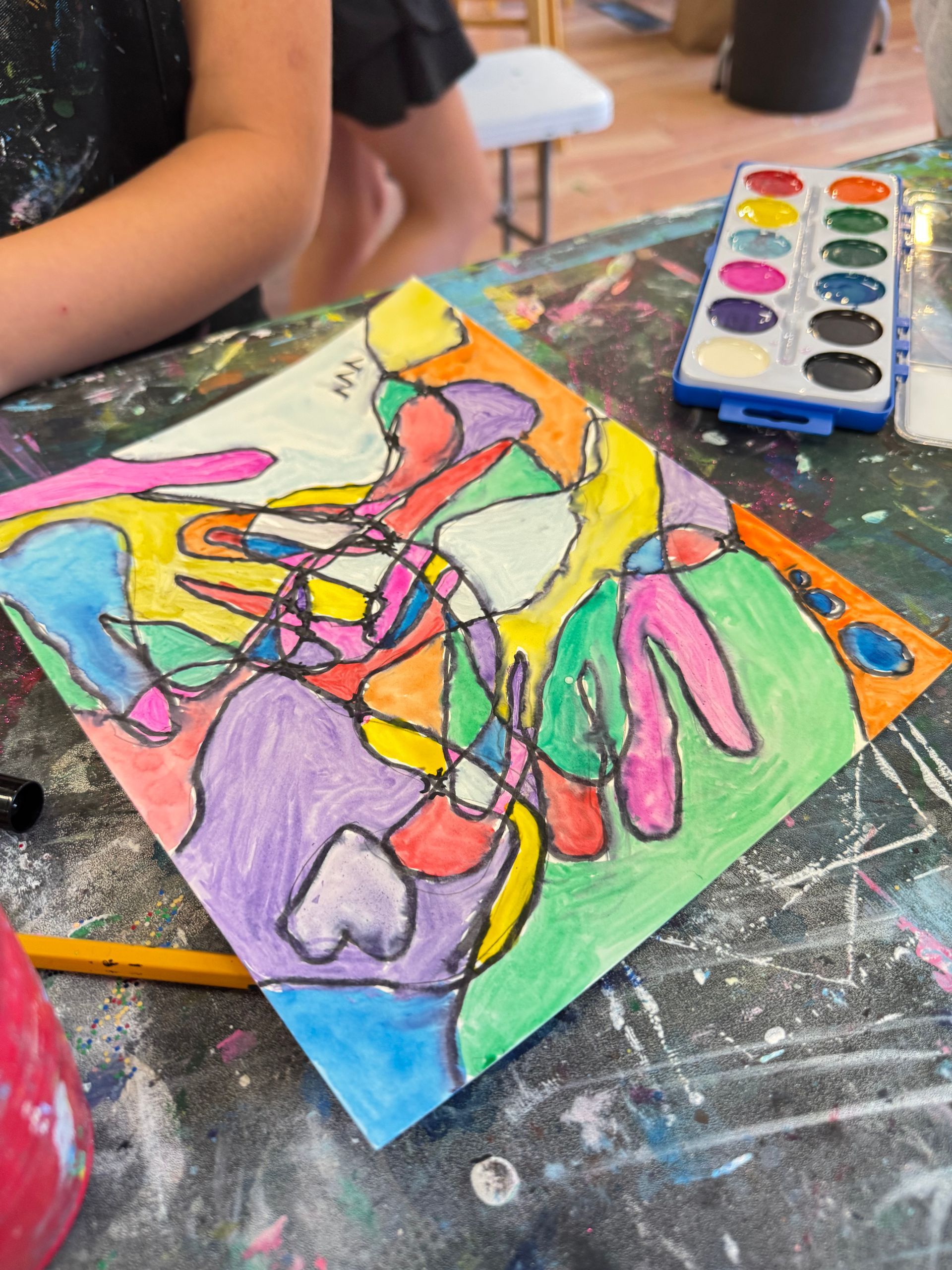 Child’s colorful abstract painting with paint palette on a messy art table
