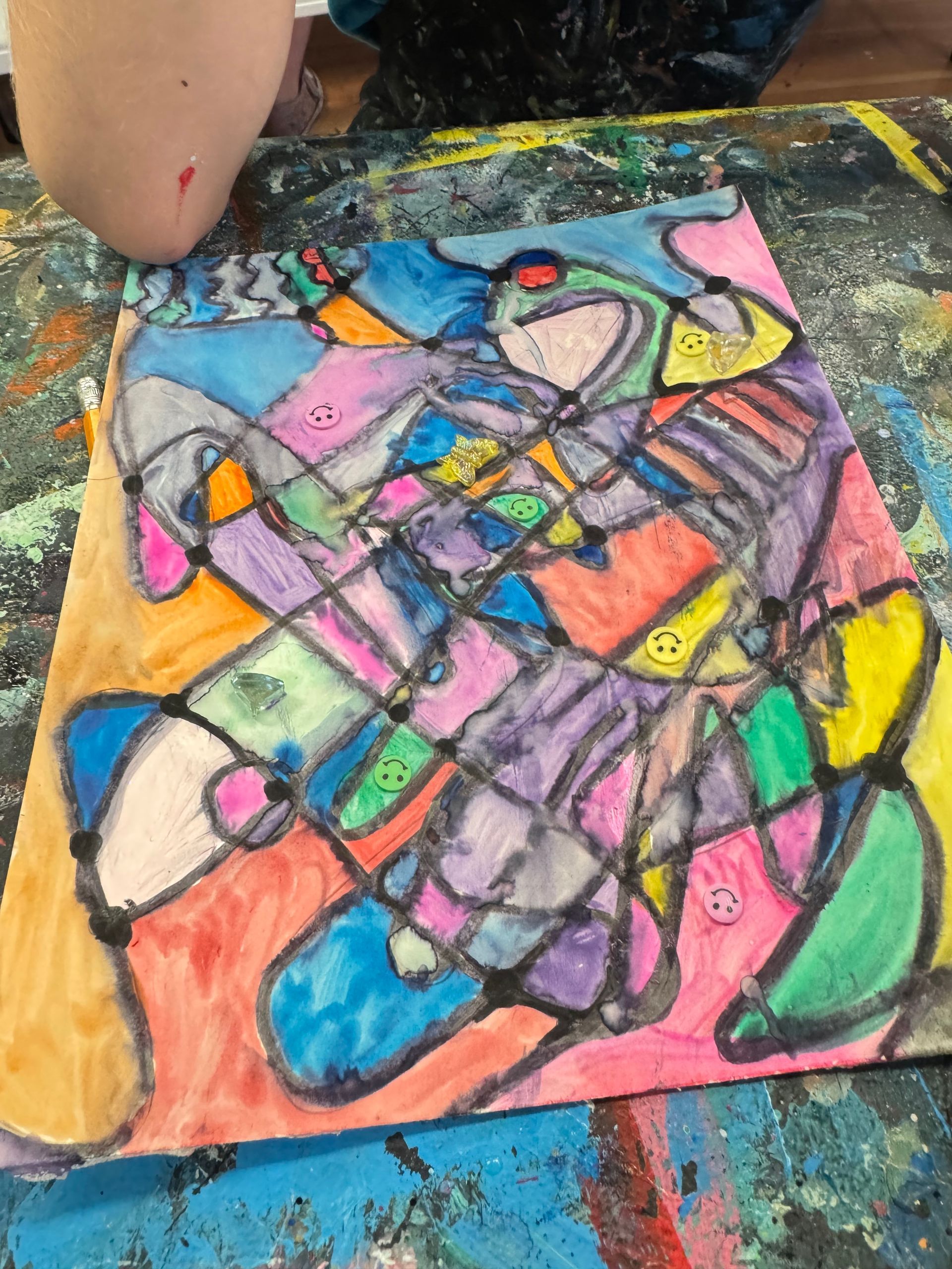 Colorful abstract chalk drawing on pavement, with black outlines and bright pink, blue, green, yellow, and orange shapes.