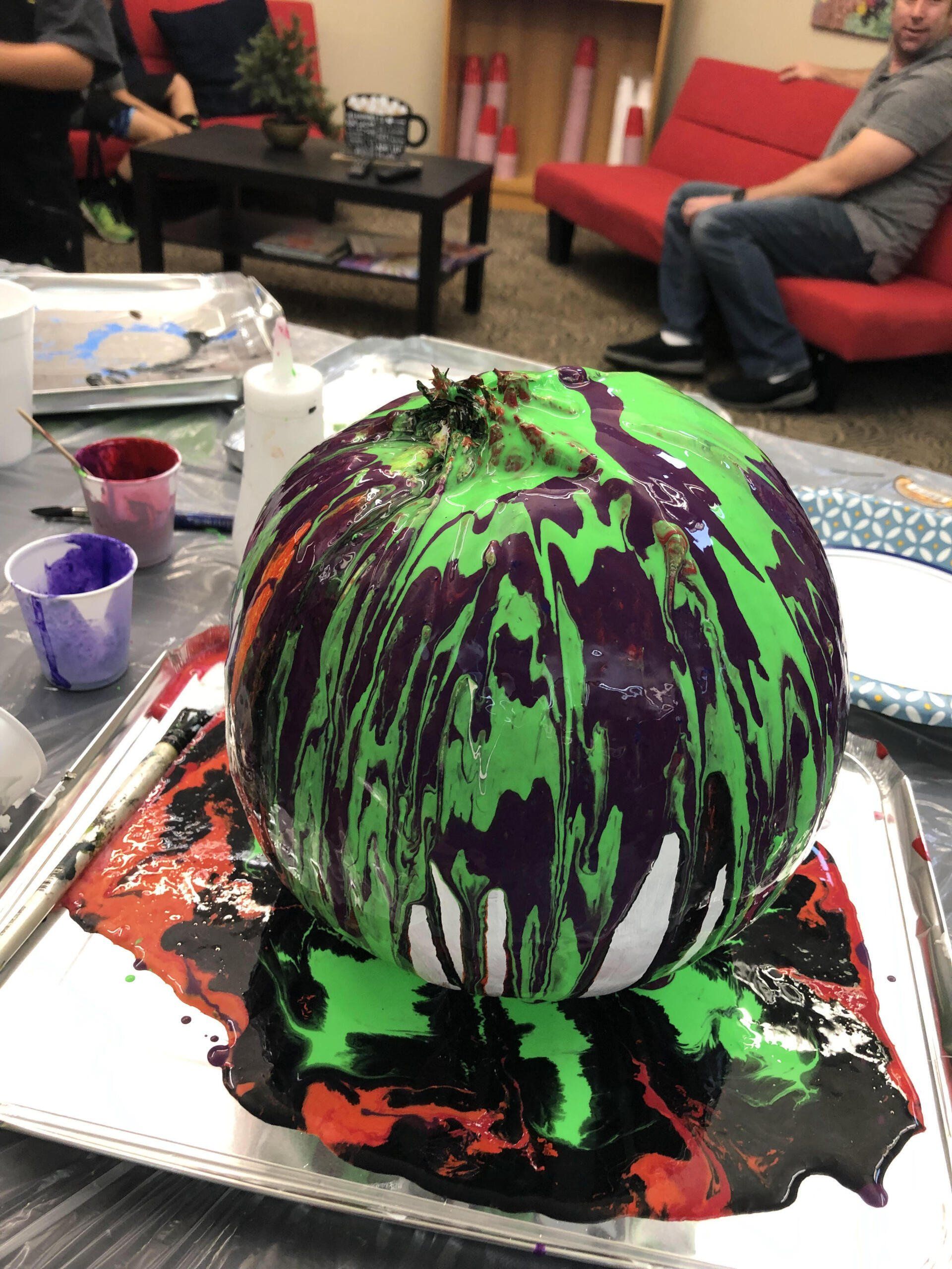 A pumpkin is covered in green and purple paint