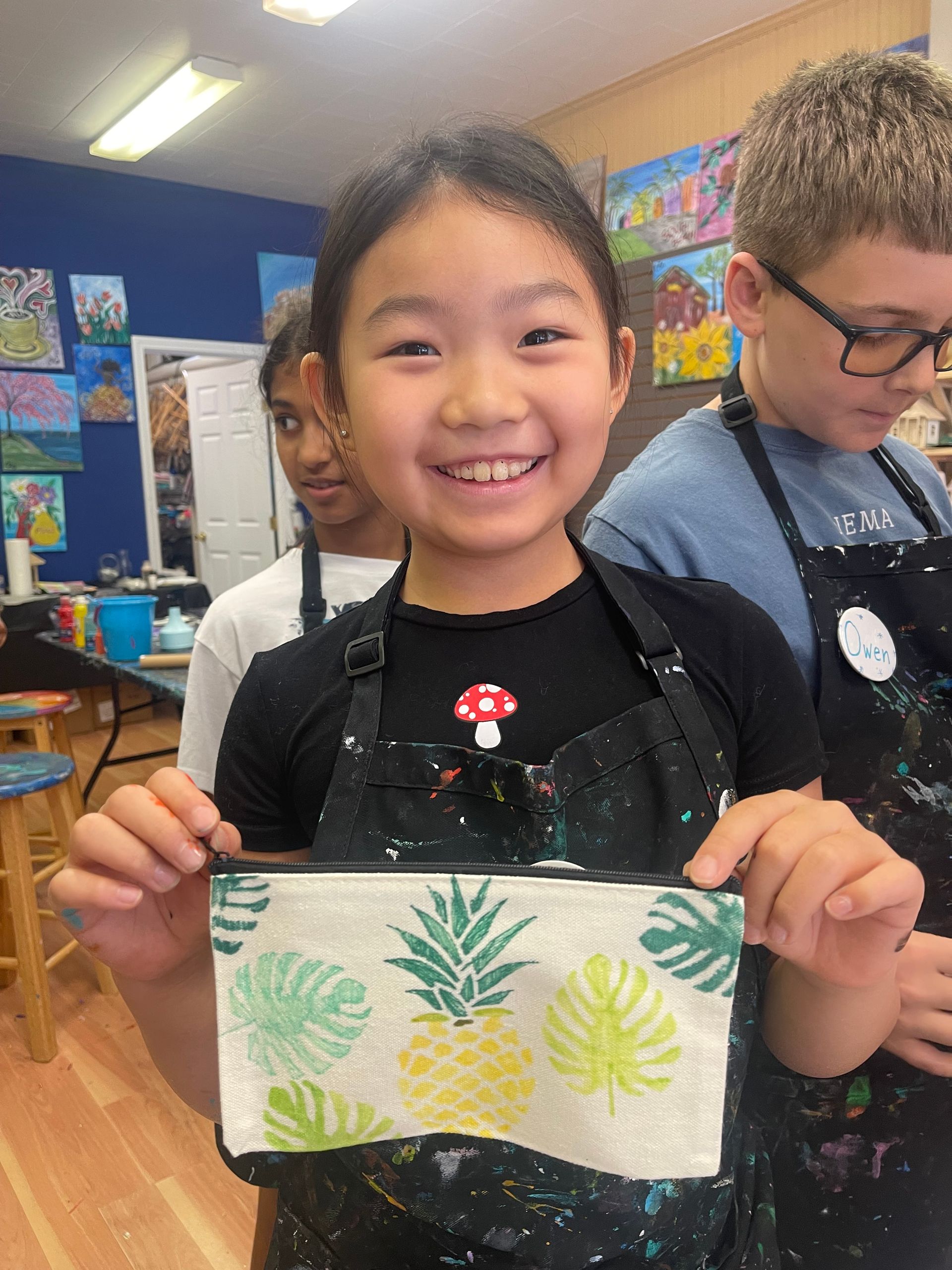 A young girl is holding a purse with pineapples and leaves on it.