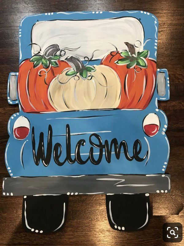 A blue truck with pumpkins in the back and the words welcome written on it