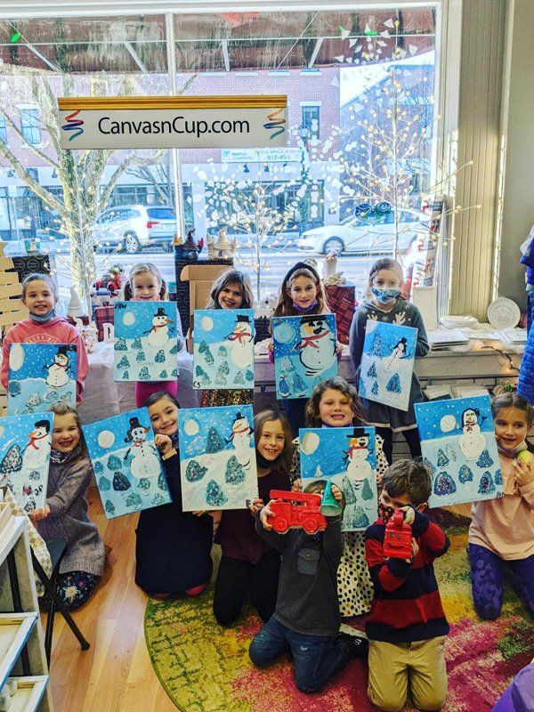 Group of kids posing with painted canvases