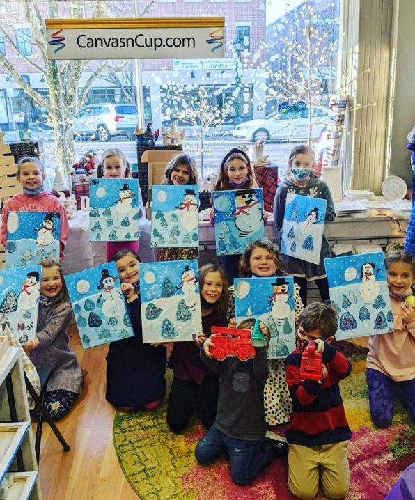 A group of children are holding up their paintings under a sign that says canvascup.com