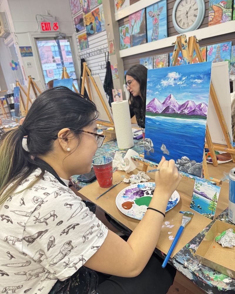 Artist painting a seascape at an easel in a colorful art studio