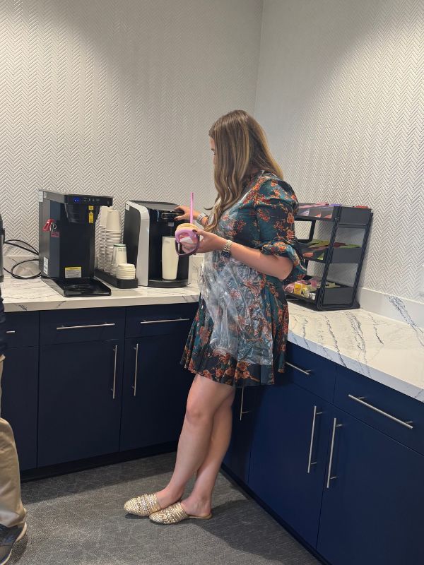 Woman in a blue patterned dress apinting remotely.