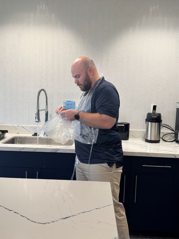  Boston Scientific employee unpacking painting items from a plastic bag near a sink and countertop.