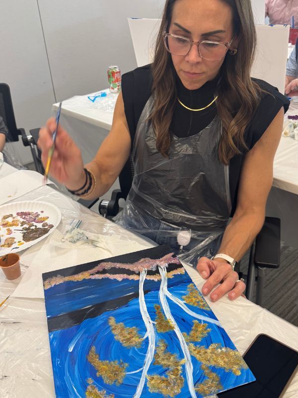  Boston Scientific team member painting birch trees with gold accents at a table.