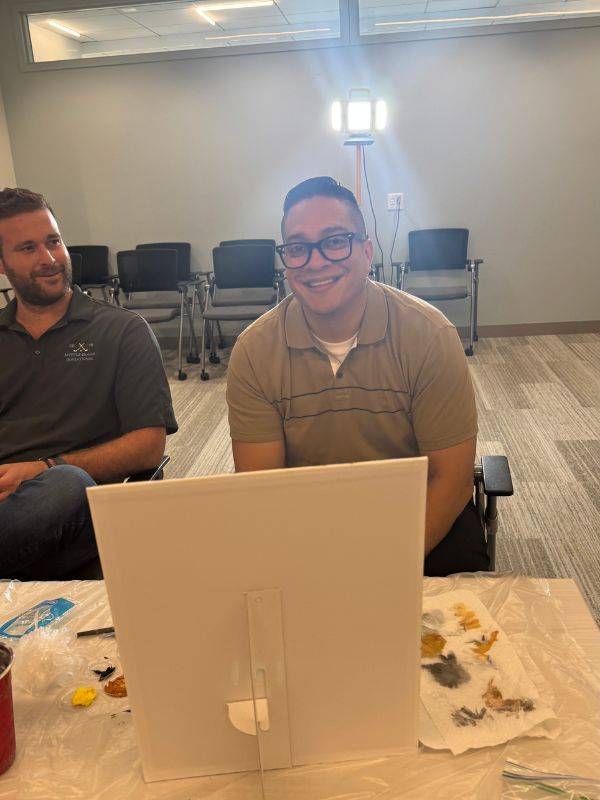 Two smiling  Boston Scientific employees seated at a table at a team building paint party