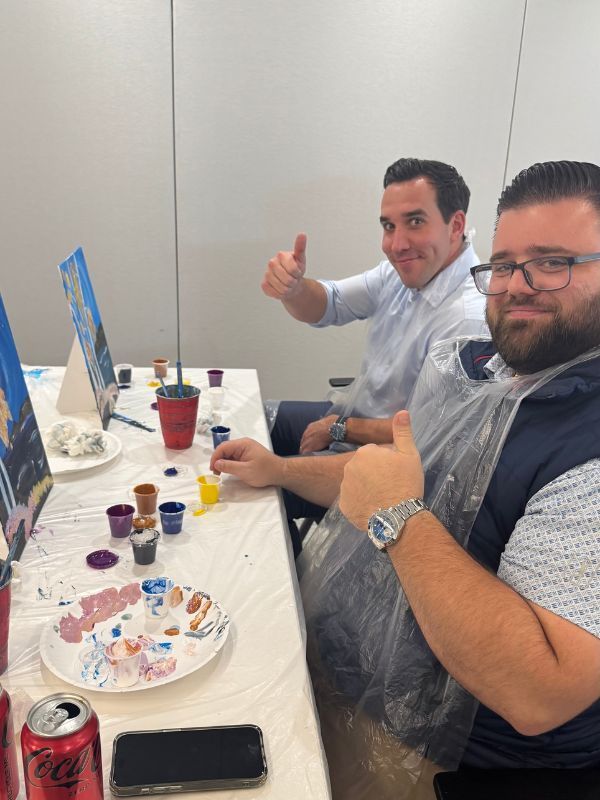 Boston Scientific employees  at a table with cupcakes and drinks, one giving a thumbs-up in a casual office celebration.