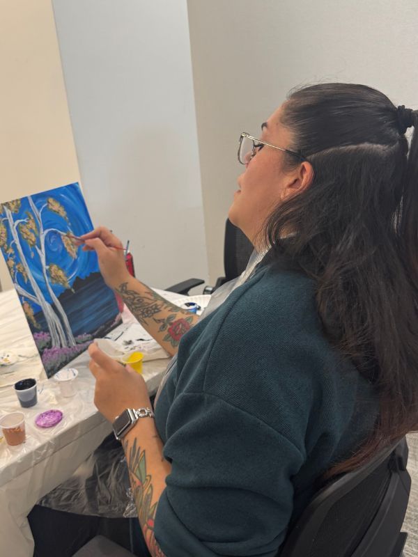 Woman painting remotely, with brushes and paint on a nearby table