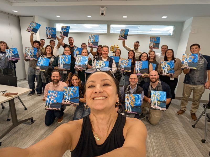 Group selfie of Boston Scientific employees holding blue booklets in a bright meeting room