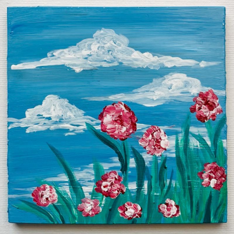 Painting of pink flowers and white clouds against a blue sky, on a wooden square.