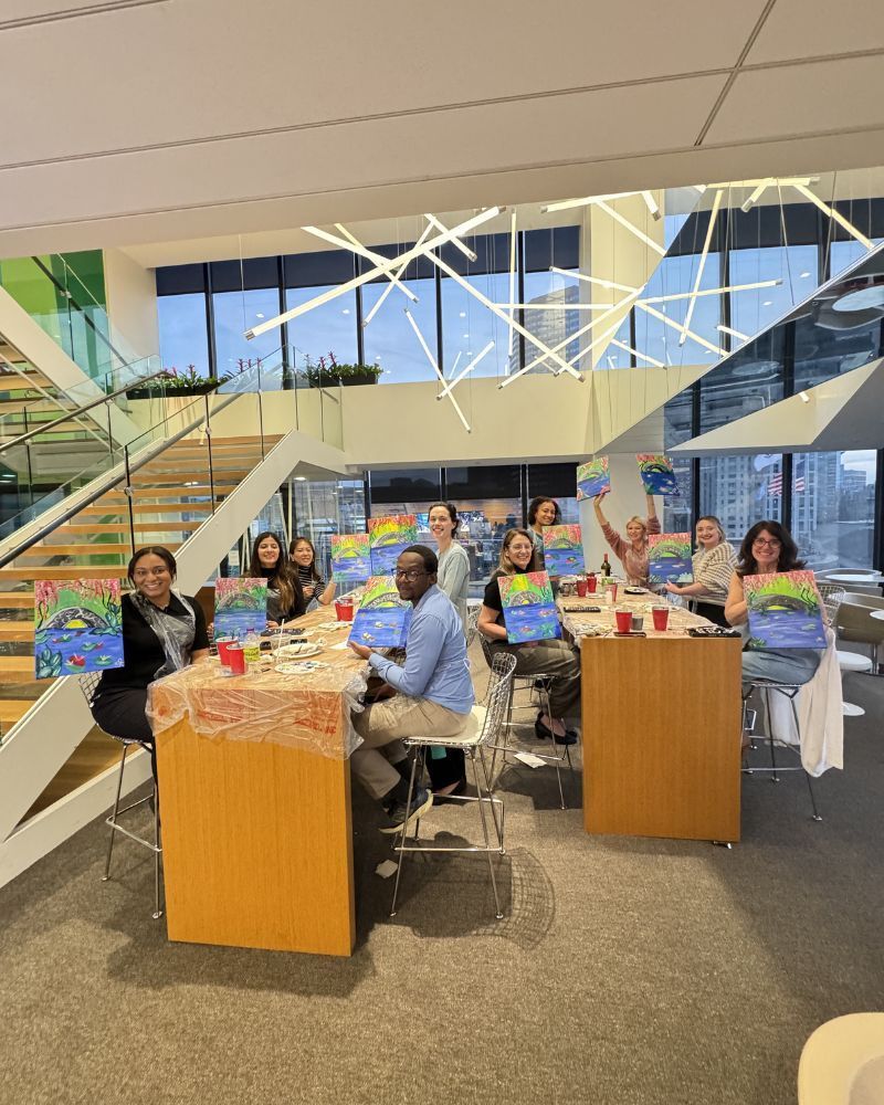 People seated at tables in a bright atrium, surrounded by colorful displays and artwork.