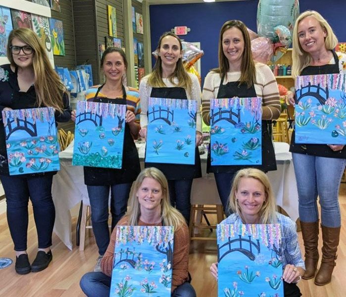 Women holding painted canvases