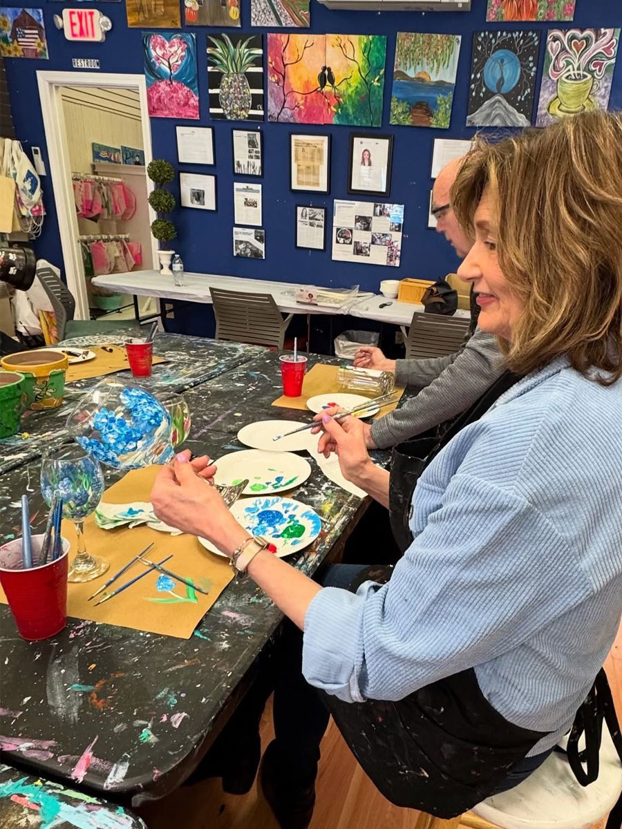 A group of people are sitting at a table painting.