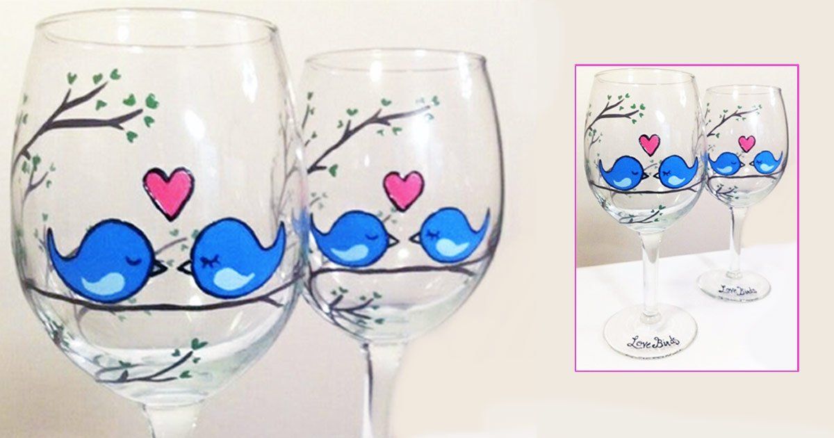 Two wine glasses with blue birds and hearts painted on them.