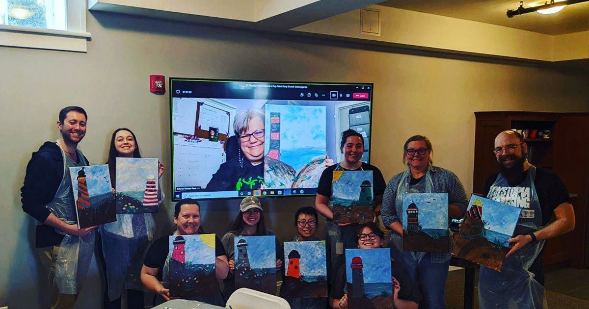 Group posing with paintings for virtual painting class