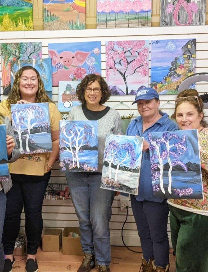 people holding painted canvases