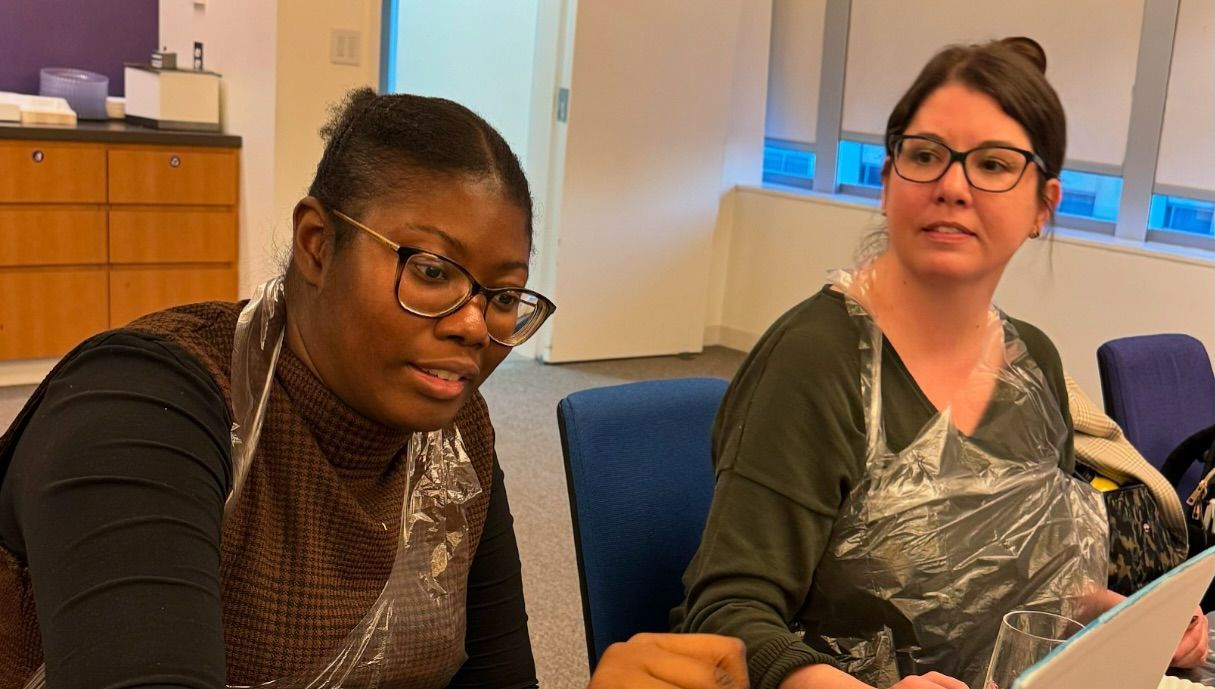Two women are sitting at a table looking at a piece of paper.