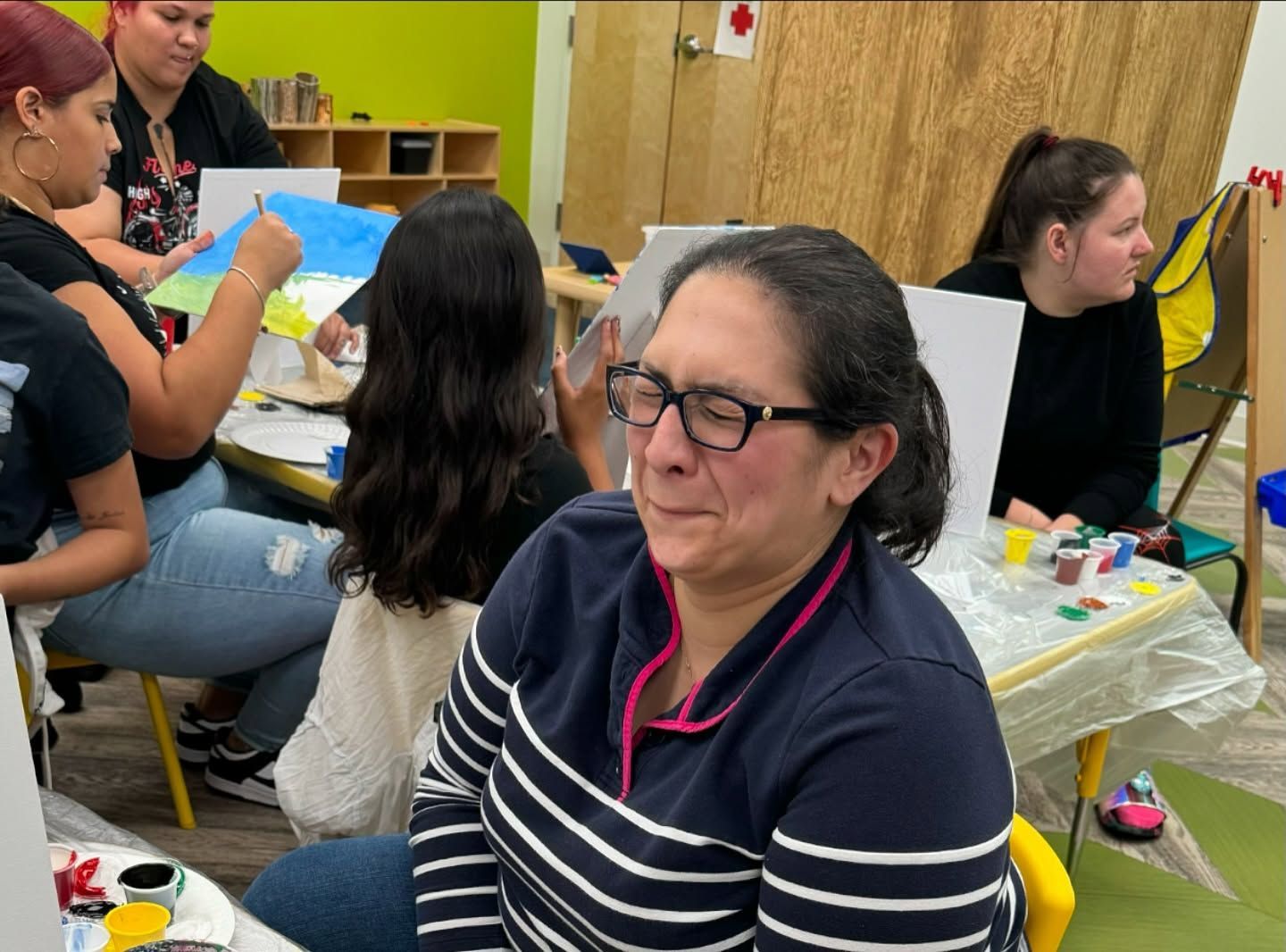 A woman wearing glasses is sitting at a table with other people.
