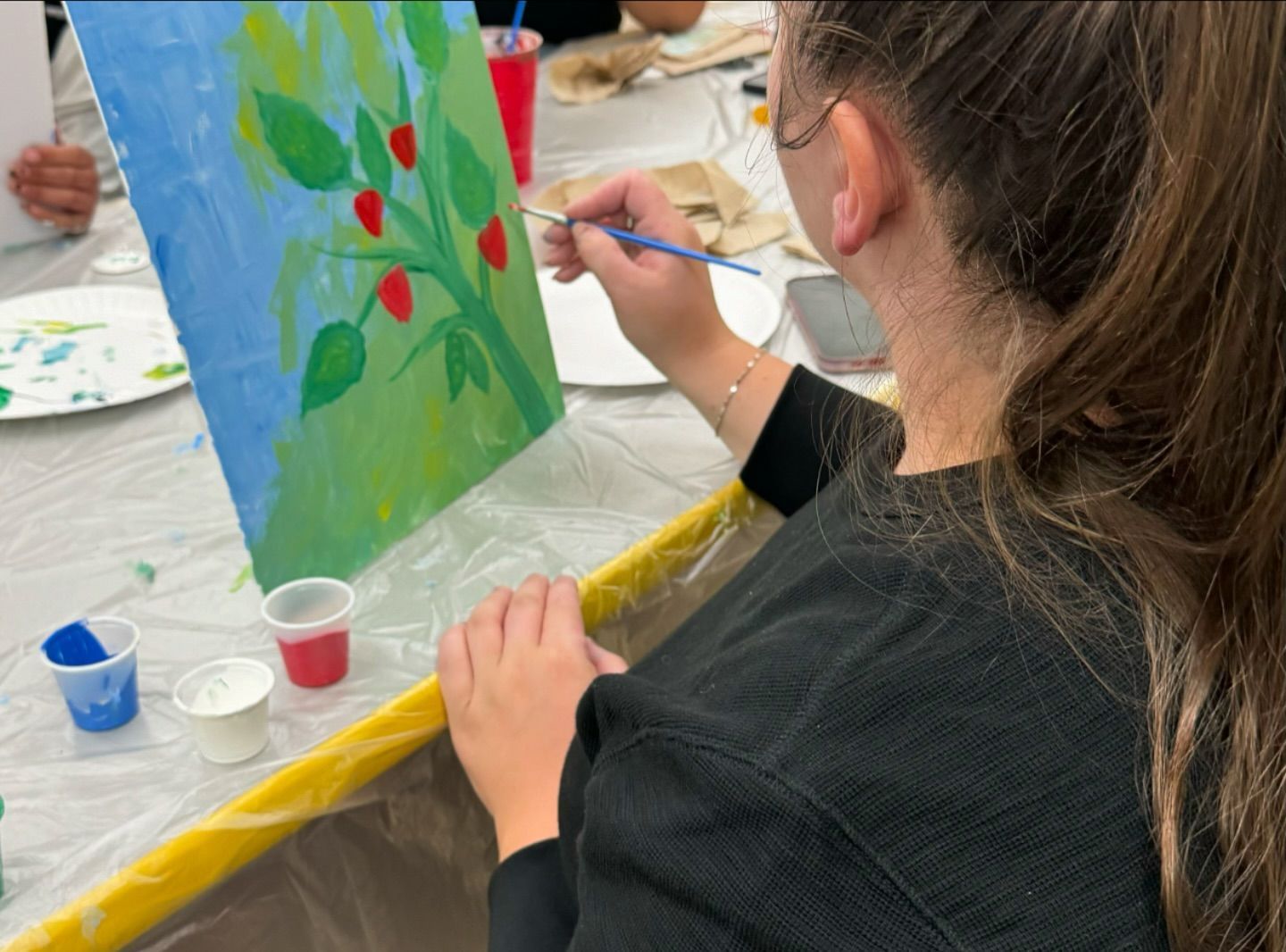 A woman is painting a picture of strawberries on a canvas.