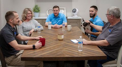 a group of people are sitting around a table having a meeting