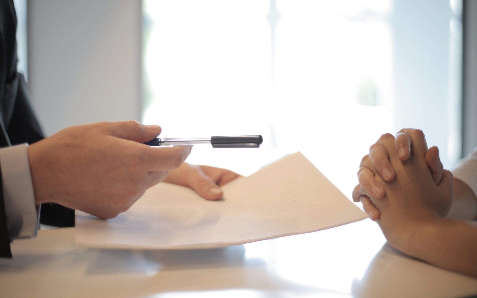 a person holding a pen over a piece of paper