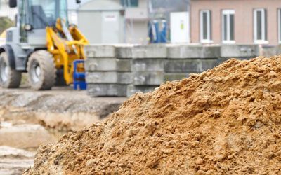 a pile of dirt in a yard with a bulldozer in the background