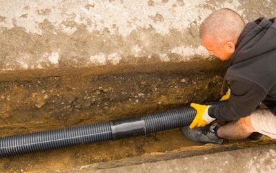 A man is re-installing a pipe in the ground