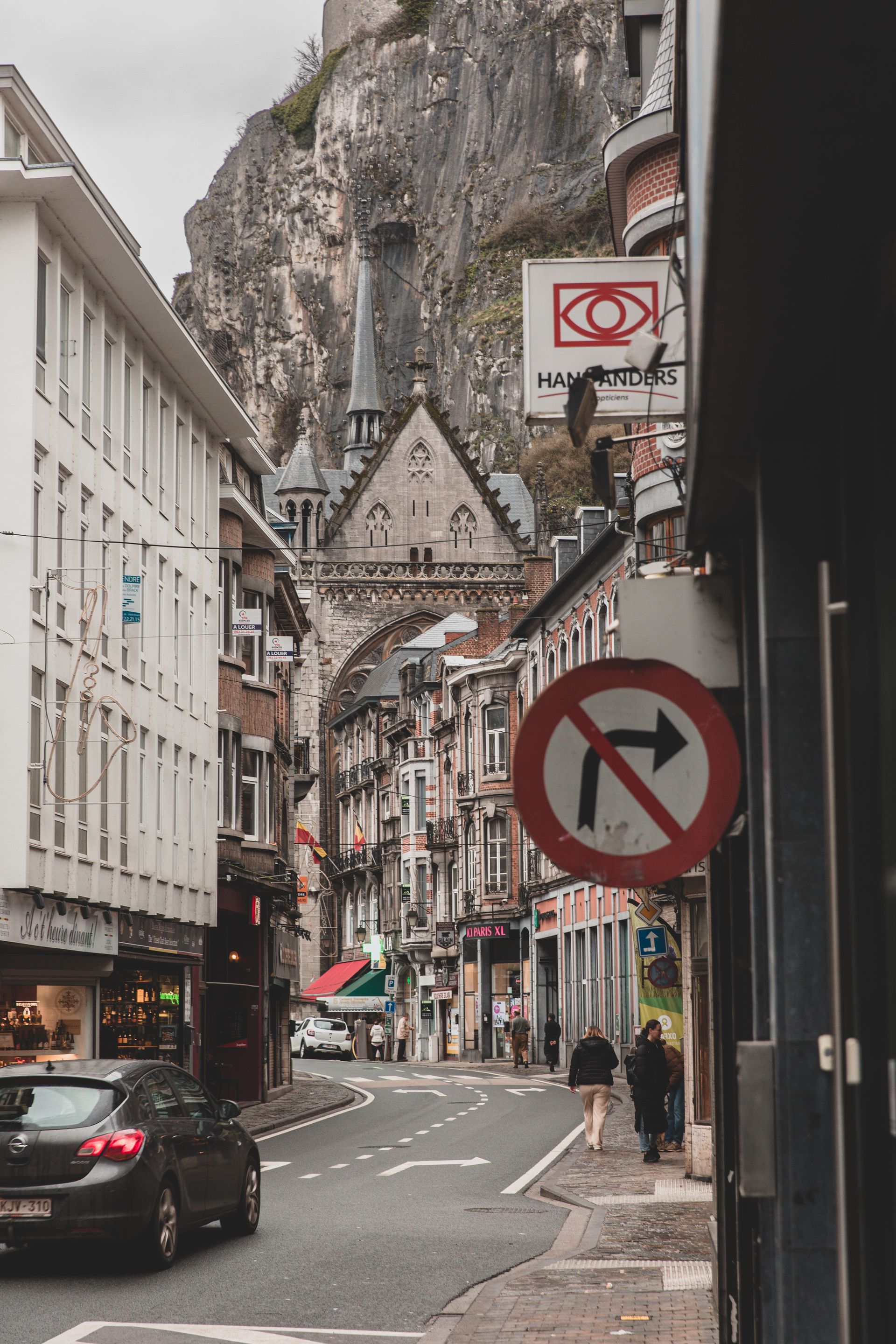 Historische architectuur van Dinant onder een betoverende regenbui, met de ui-vormige koepels die uitsteken tegen een dramatisch bewolkte hemel, vastgelegd door Pixels Fotografie