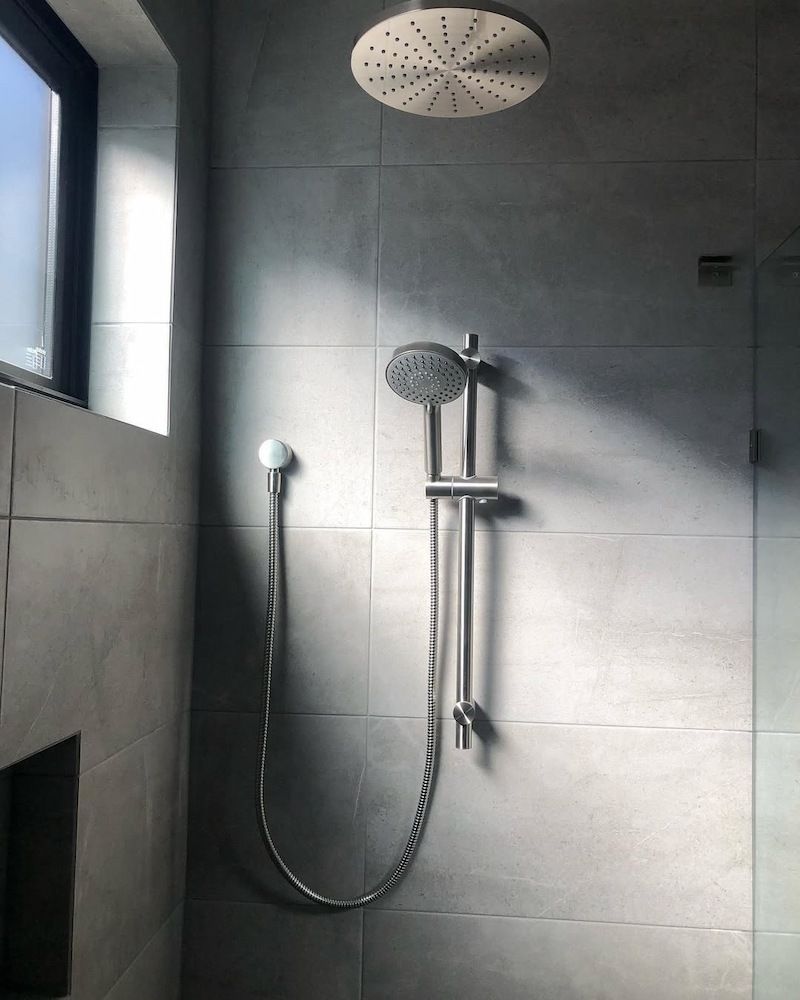 A Shower Head is Hanging From the Ceiling in a Bathroom Next to a Window — Peak Plumbing and Gas Fitting in Yamba, NSW