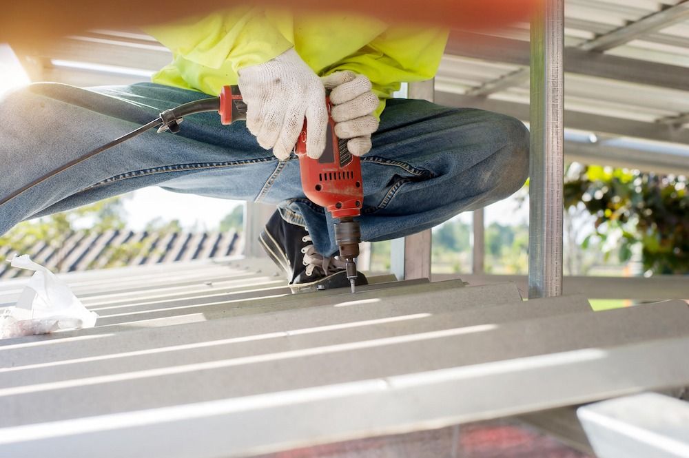 A Man is Using a Drill to Drill a Hole in a Metal Structure — Peak Plumbing and Gas Fitting in Yamba, NSW 