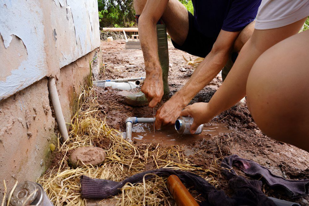 Two People Are Working on a Pipe in the Mud — Peak Plumbing and Gas Fitting in Grafton, NSW