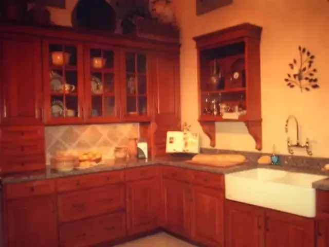 Warm-toned kitchen with wooden cabinets, tiled backsplash, sink, and countertop decor