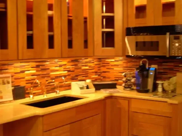 Warm-toned kitchen with wood cabinets, mosaic tile backsplash, sink, and coffee maker on the counter