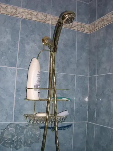 Shower caddy with toiletries in a blue-tiled bathroom shower
