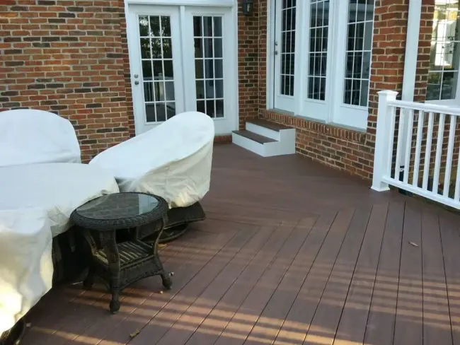 Covered patio with wicker seating, round table, and sliding glass doors on a sunny day