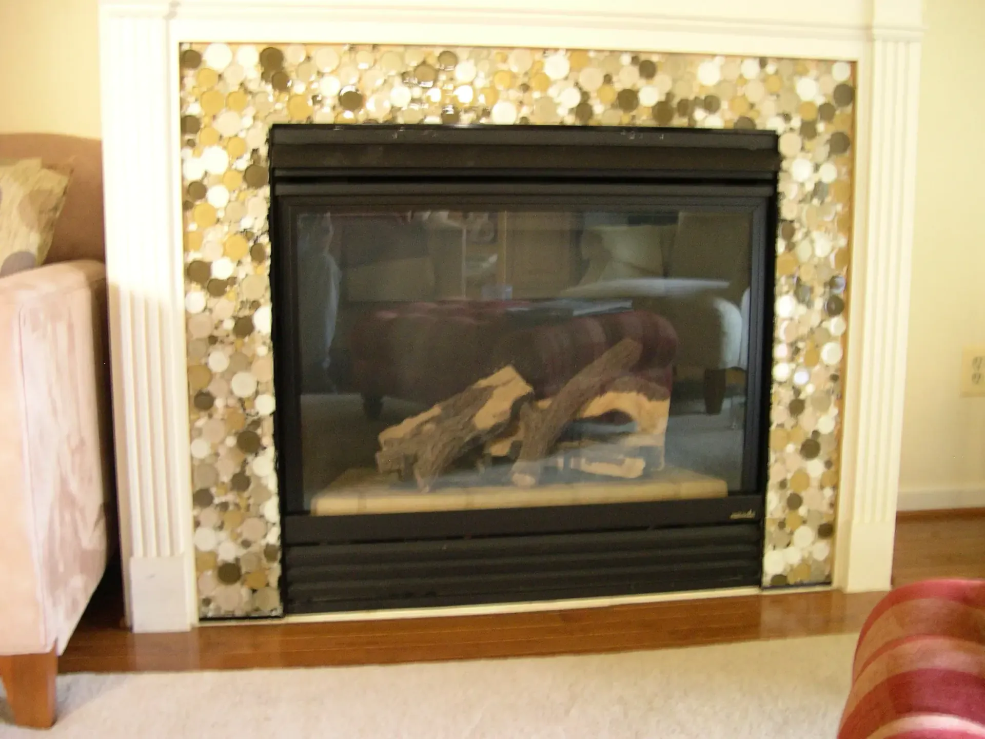 Fireplace with black glass insert and decorative tile surround in a living room.