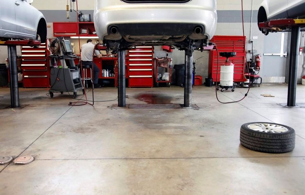 Officina meccanica con un'auto sollevata su un ponte e uno pneumatico sul pavimento del garage.